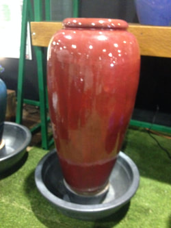 Picture of a lavish, slim red jar fountain. 
