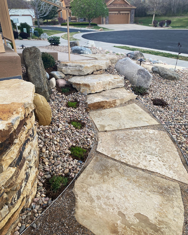 Custom xeriscape walkway for a side yard using siloam stone, river rock ground covering, drip irrigation, and drought tolerant plant selection in Arvada, Colorado. 