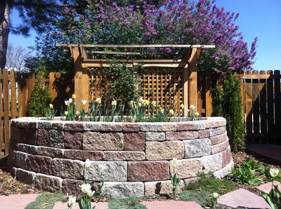 Raised garden bed and stone walkways for a home backyard perennial pollinator garden landscape in Arvada, Colorado. 