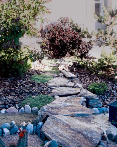Custom siloam stone walkway and river stone ground covering for a water wise home landscape in Arvada, Colorado. 