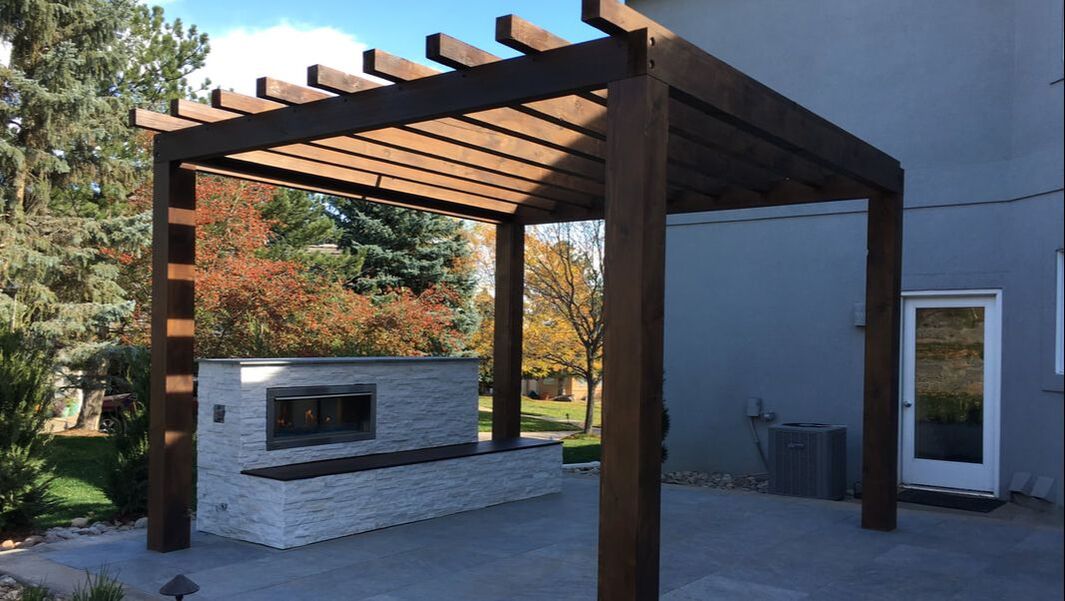 Modern gas burning outdoor fireplace and wooden pergola.
