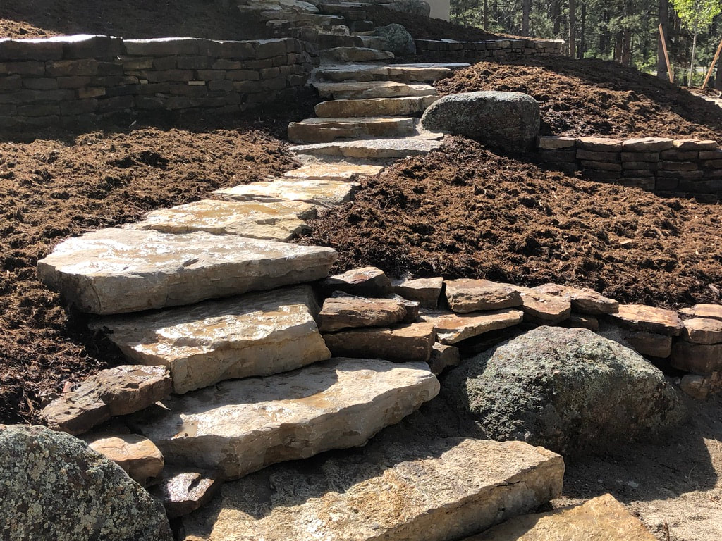 Photo of rustic retaining walls using river rock and mulch for a mountainous xeriscape. 