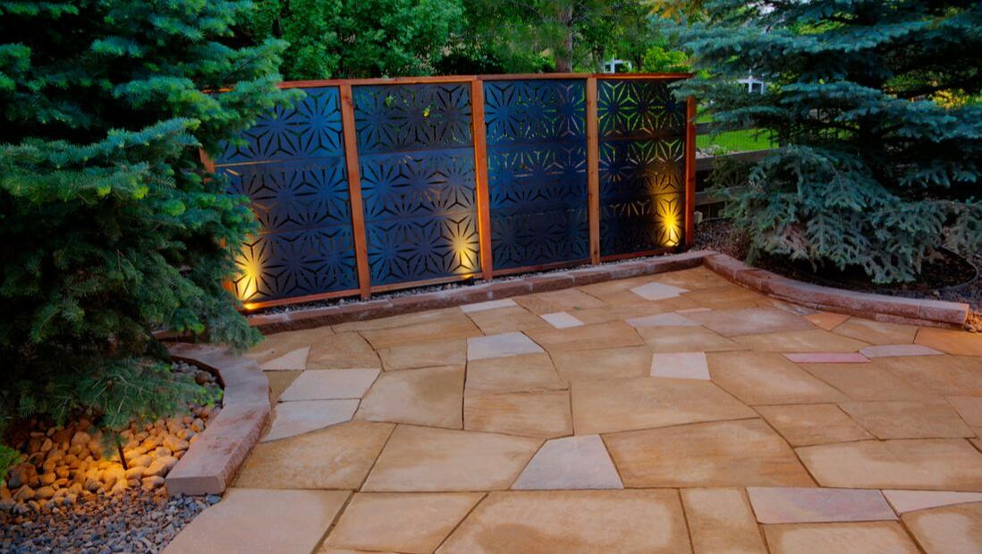 Photo of a stone patio with privacy screen and low voltage feature lighting. 