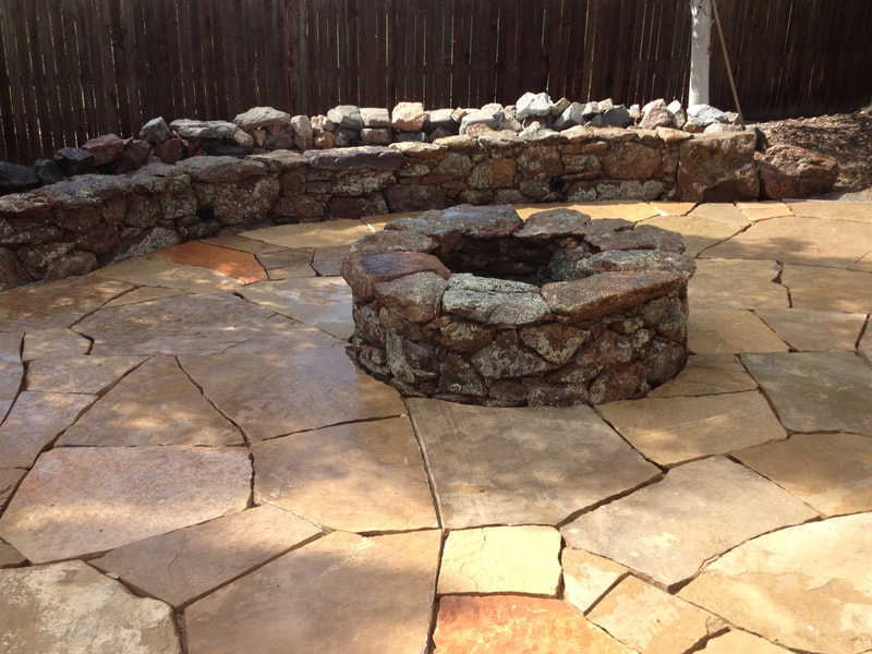 Rustic wood-burning fire pit with a stone patio in Golden, Colorado.